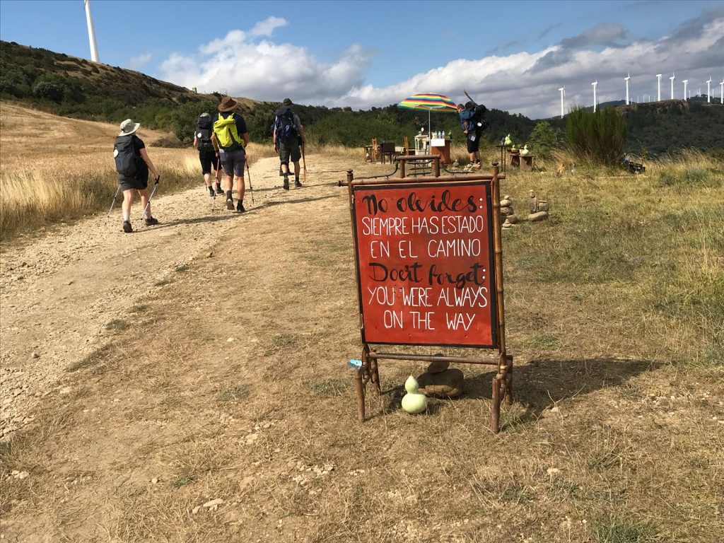 Camino Frances de Santiago: pilgrims passing by a sign that reads: remember you were always on the way
